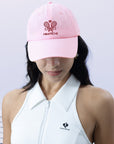 Pink tennis cap with embroidered logo and adjustable ribbon on the back strap.