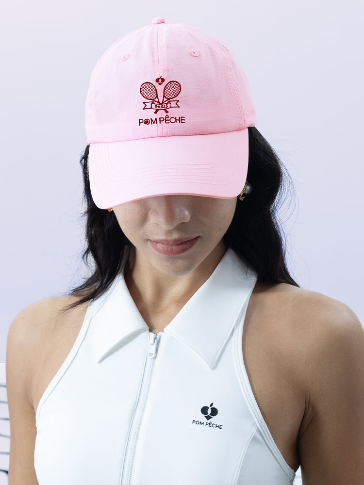 Pink tennis cap with embroidered logo and adjustable ribbon on the back strap.