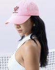 Pink tennis cap with embroidered logo and adjustable ribbon on the back strap.