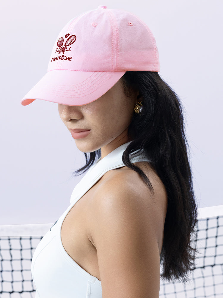Pink tennis cap with embroidered logo and adjustable ribbon on the back strap.