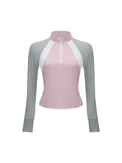 Pink long-sleeve fitted top with a half-zip neckline and subtle logo detail, styled on the tennis court.