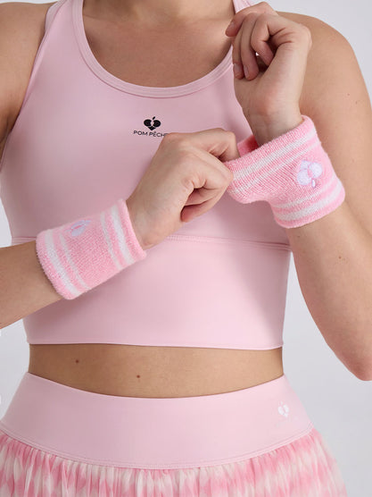 Soft pink tennis wristbands with white stripes, featuring logo details.