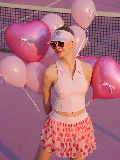 Light pink zip-front tennis tank with a collar and subtle logo, offering a chic look for on-court wear.