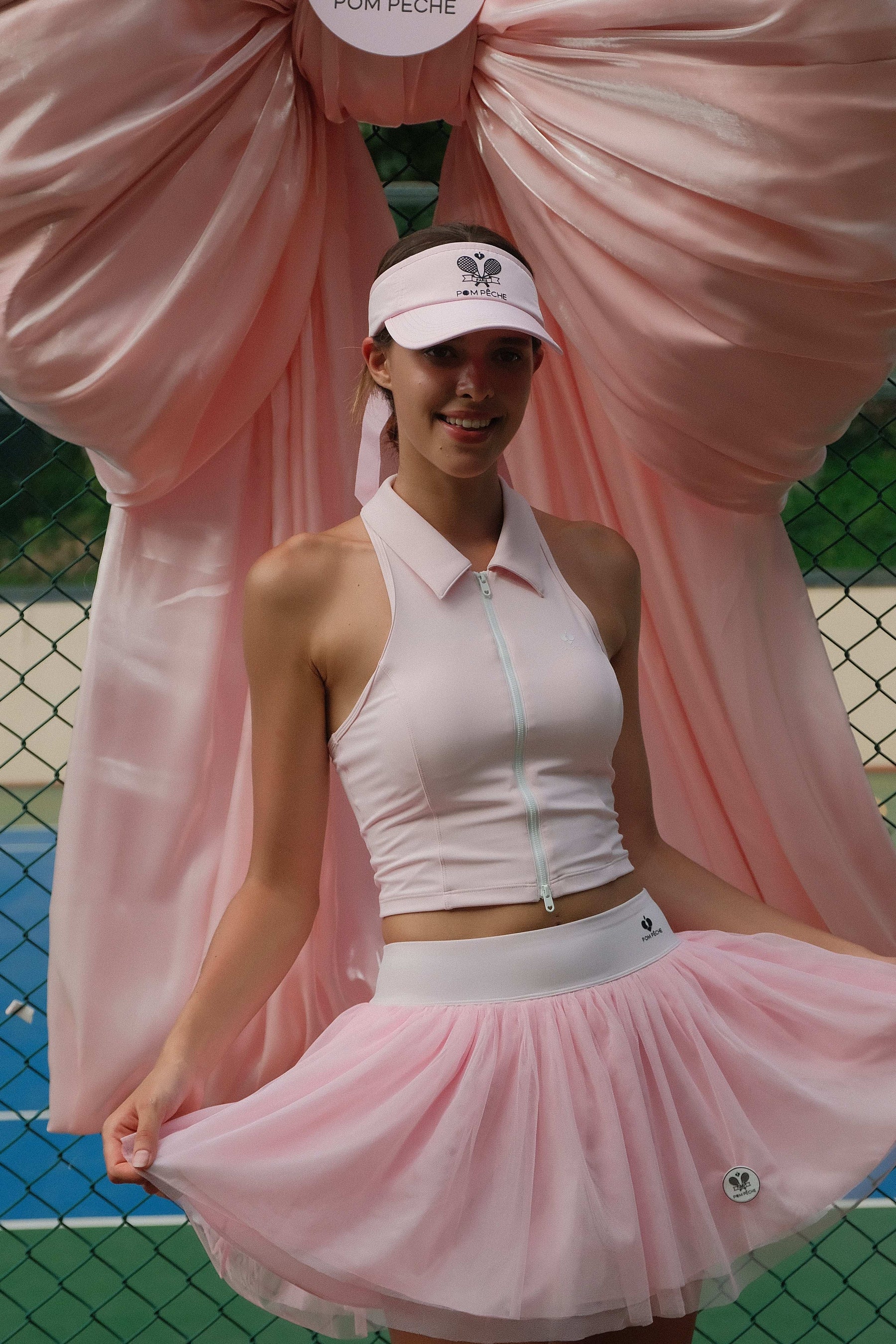Pink puff tulle tennis skirt styled with sleeveless top, highlighting flowy layers and high-waisted tennis skirt movement on court.