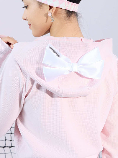 Soft pink zip-up hoodie with bow detail on the hood and embroidered logo, perfect for warm-ups or everyday wear.