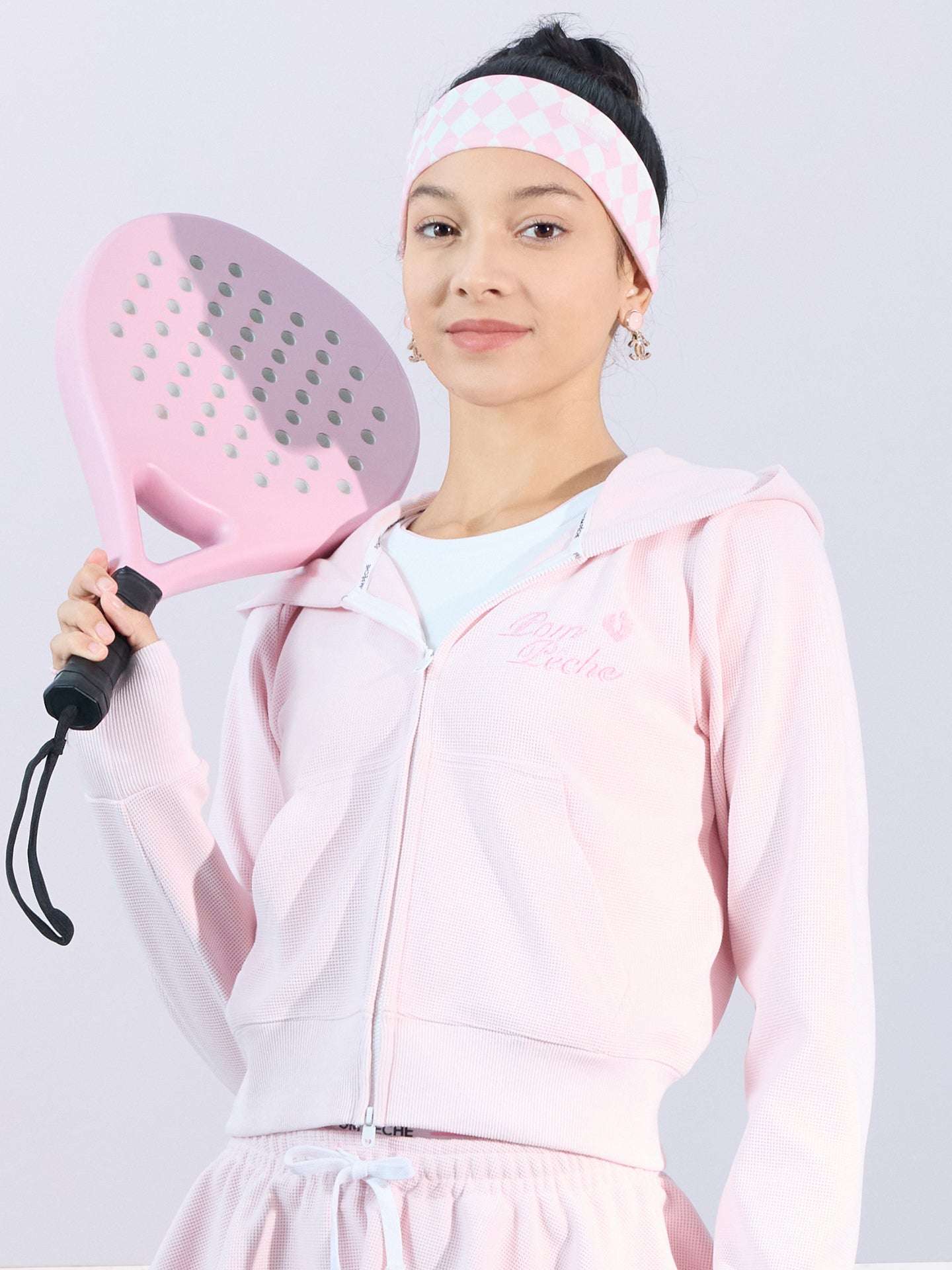 Soft pink zip-up hoodie with bow detail on the hood and embroidered logo, perfect for warm-ups or everyday wear.