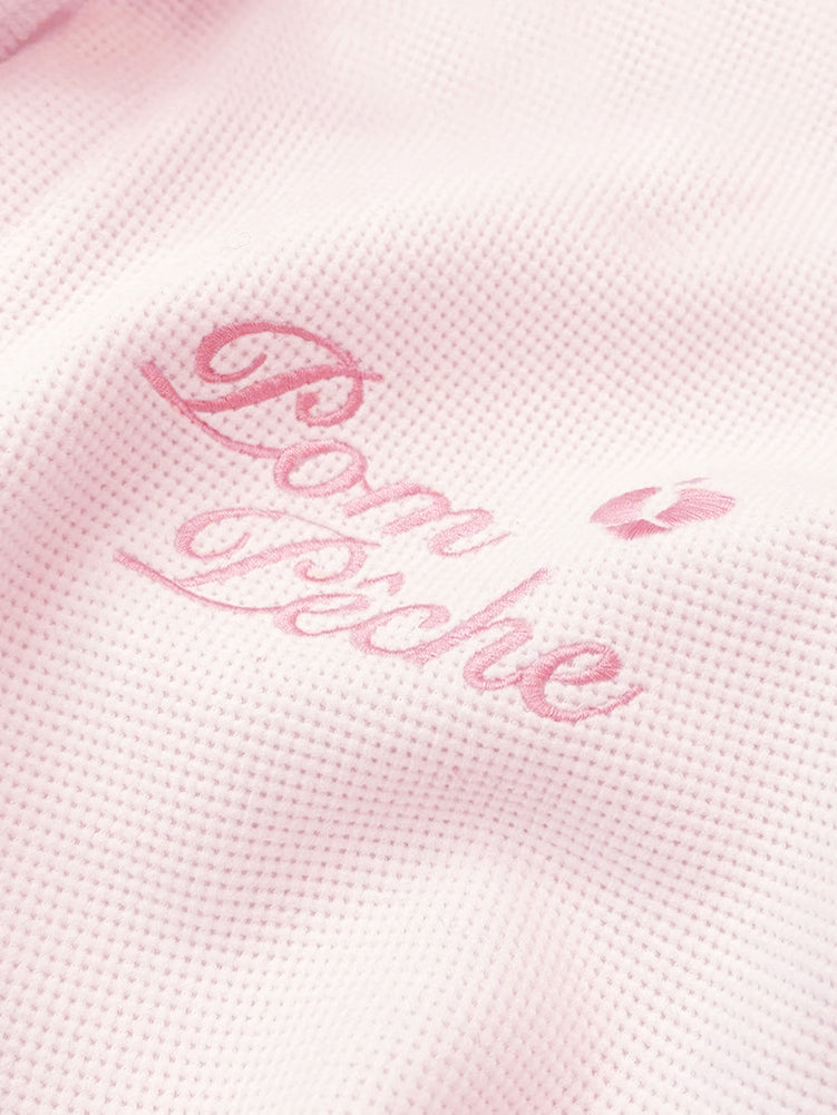 Soft pink zip-up hoodie with bow detail on the hood and embroidered logo, perfect for warm-ups or everyday wear.