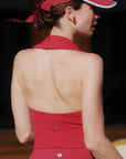 Woman wearing a red dress with a halter neck and visor in an indoor setting