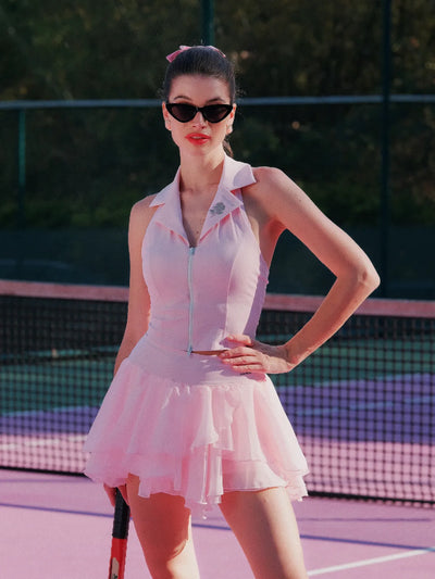 Woman in a white tennis dress and sunglasses on a tennis court