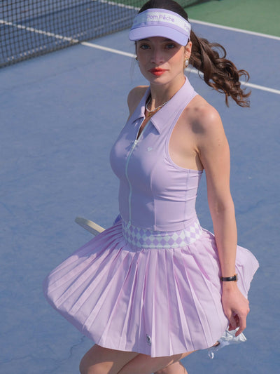 A purple pleated tennis skirt with an argyle waistband is shown flowing on court, styled as a lightweight athletic skirt for training.