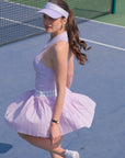 Woman in a lavender tennis outfit on a tennis court