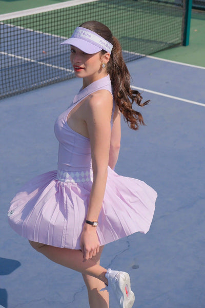 Woman in a lavender tennis outfit on a tennis court