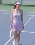 Woman in a lavender tennis outfit on a tennis court
