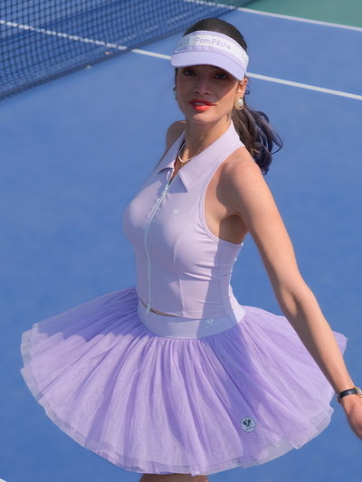 Model wearing a lavender tulle puff tennis skirt on court, highlighting airy layered mesh and a high-waisted athletic tennis skirt silhouette.