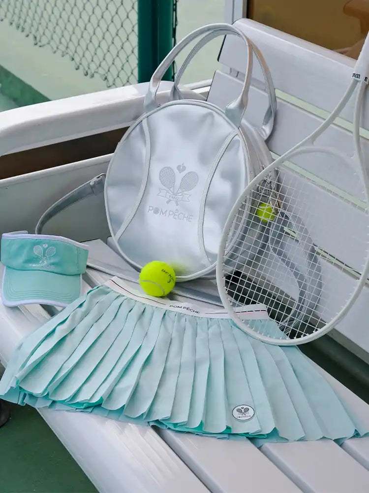 Tennis racket, visor, skirt, and ball on a chair with a tennis court background