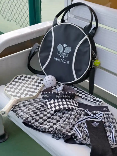 Pickleball paddle, bag, and accessories on a white surface with a blurred background