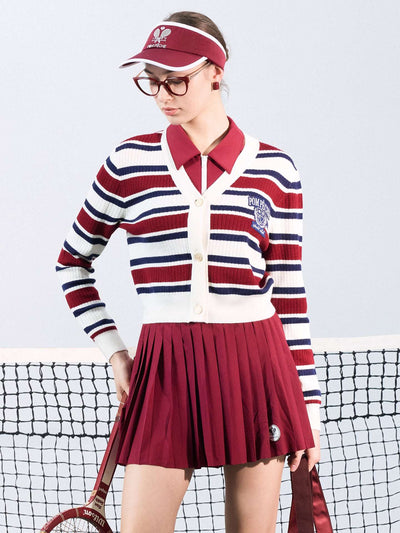 Red, navy, and white striped cardigan with a V-neck, button-down design, featuring an embroidered logo. Styled from court to café.