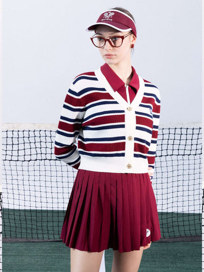 Red, navy, and white striped cardigan with a V-neck, button-down design, featuring an embroidered logo. Styled from court to café.