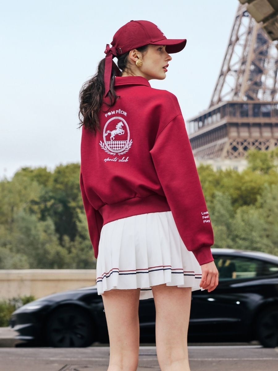 Red sweatshirt with quarter-zip design and embroidered logo on the front and back, offering a stylish and sporty look.