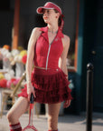 Woman in a red outfit with a tennis racket on a street.