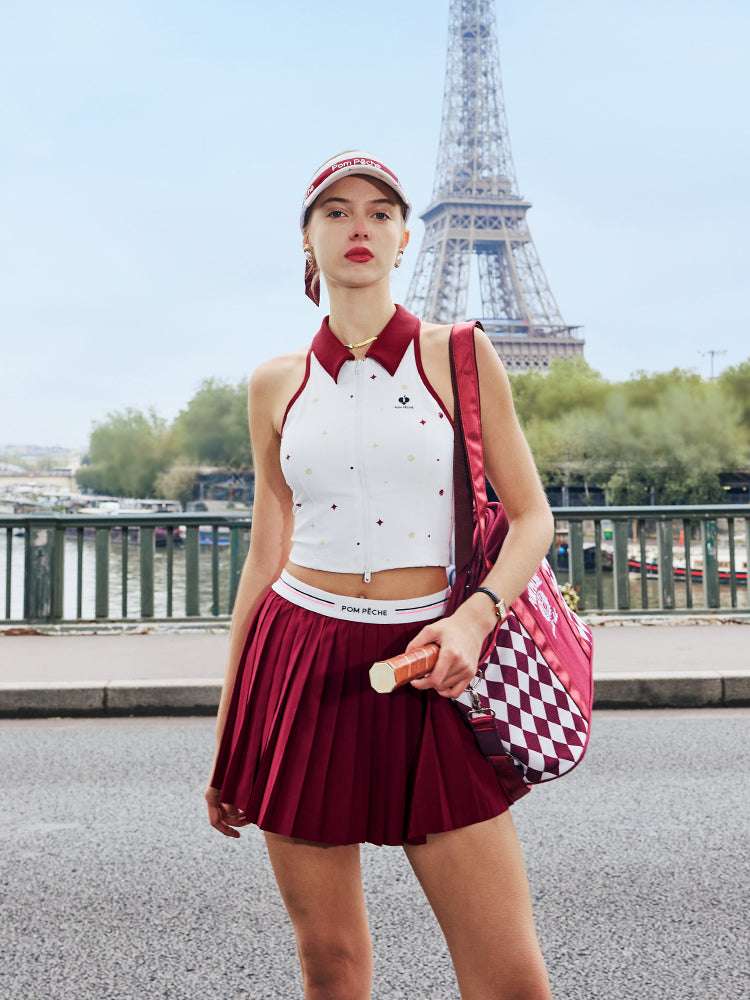 White zip-front tennis tank with red collar and star print, offering a chic, preppy look for court or city wear.