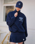 Person wearing a navy blue outfit with a matching cap, featuring logos and text.