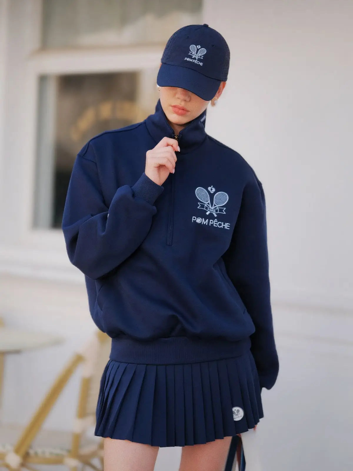 Person wearing a navy blue outfit with a matching cap, featuring logos and text.