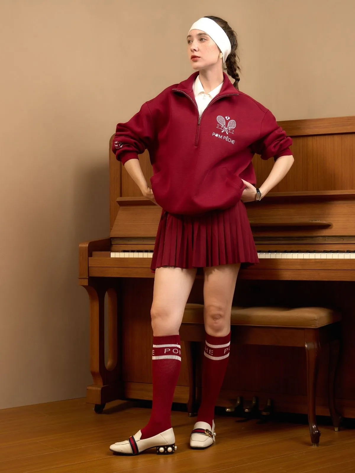 Woman in a red tracksuit standing in front of a piano