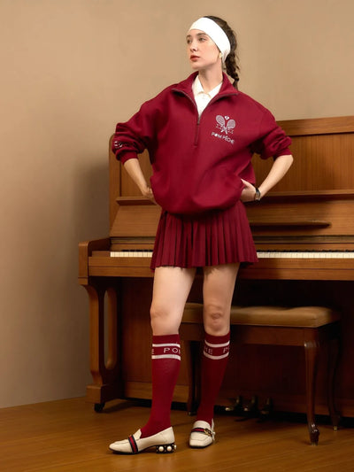 Woman in a red tracksuit standing in front of a piano