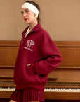 Woman wearing a red sweatshirt with a logo in front of a piano