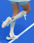 White knee-high tennis socks with sky blue stripes, bow detail, and logo embroidery.
