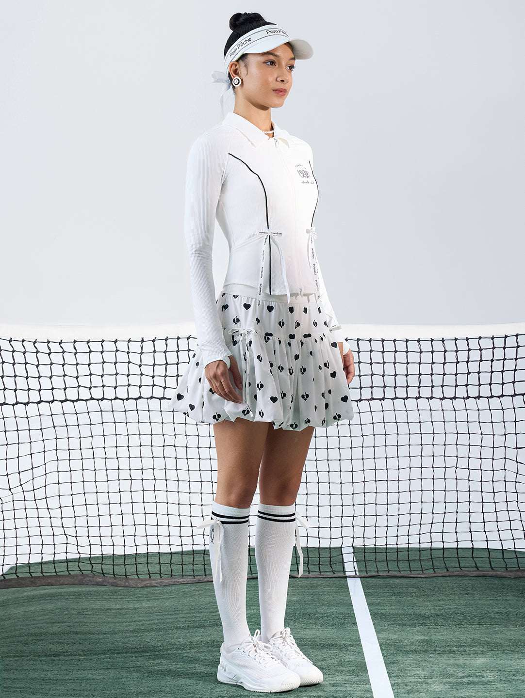 White sun-protective tennis jacket with a sculpted fit, adjustable waist ties, and dual ball pockets.