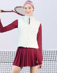 Warm white fleece vest with high-neck zip design and embroidered chest pocket, styled on the tennis court.