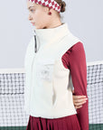 Warm white fleece vest with high-neck zip design and embroidered chest pocket, styled on the tennis court.