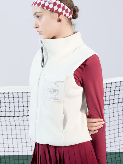 Warm white fleece vest with high-neck zip design and embroidered chest pocket, styled on the tennis court.