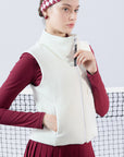 Warm white fleece vest with high-neck zip design and embroidered chest pocket, styled on the tennis court.