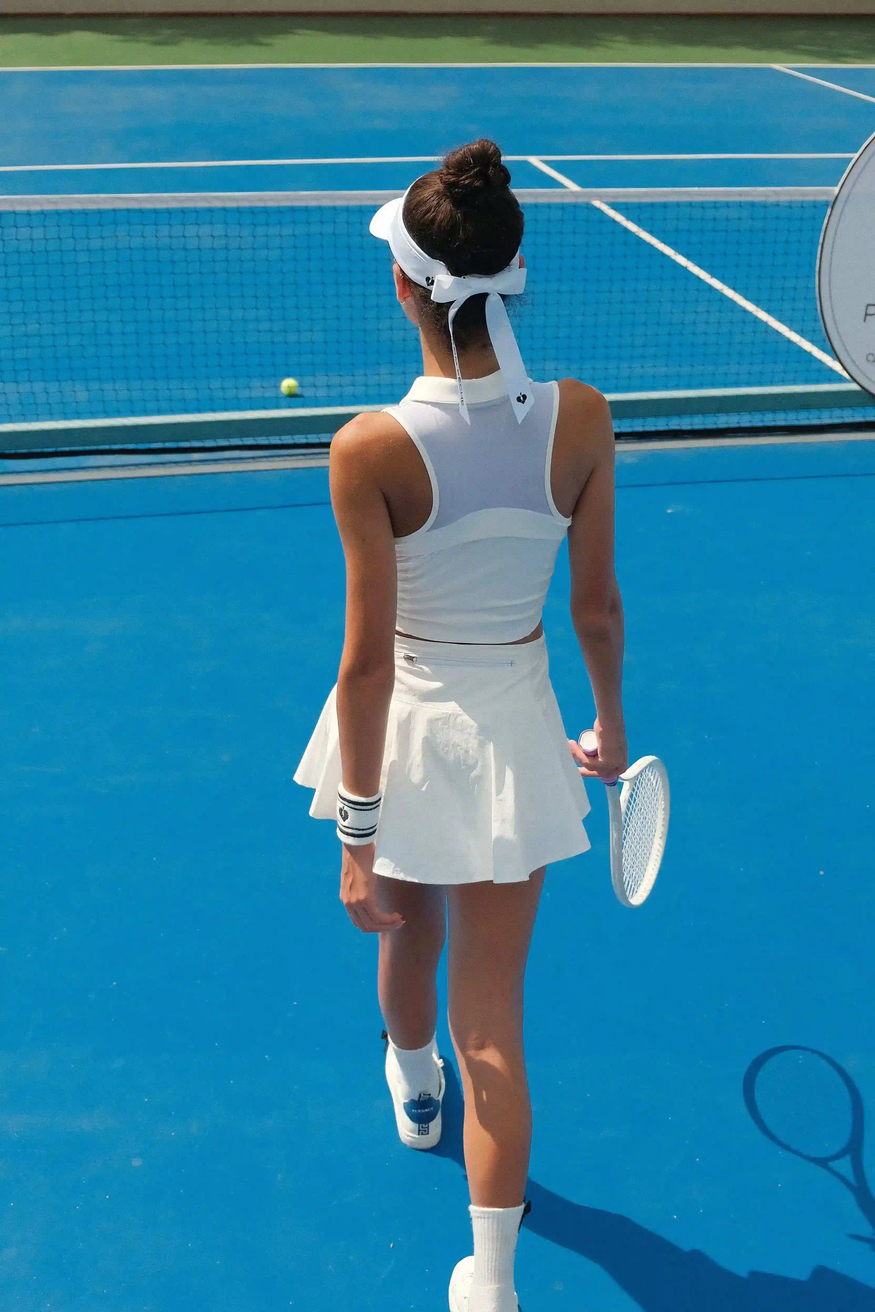White half-zip cropped tennis polo top with breathable mesh back and printed logo, designed for lightweight comfort on court.