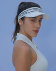 White tennis visor with a Pom Pêche logo on the band.