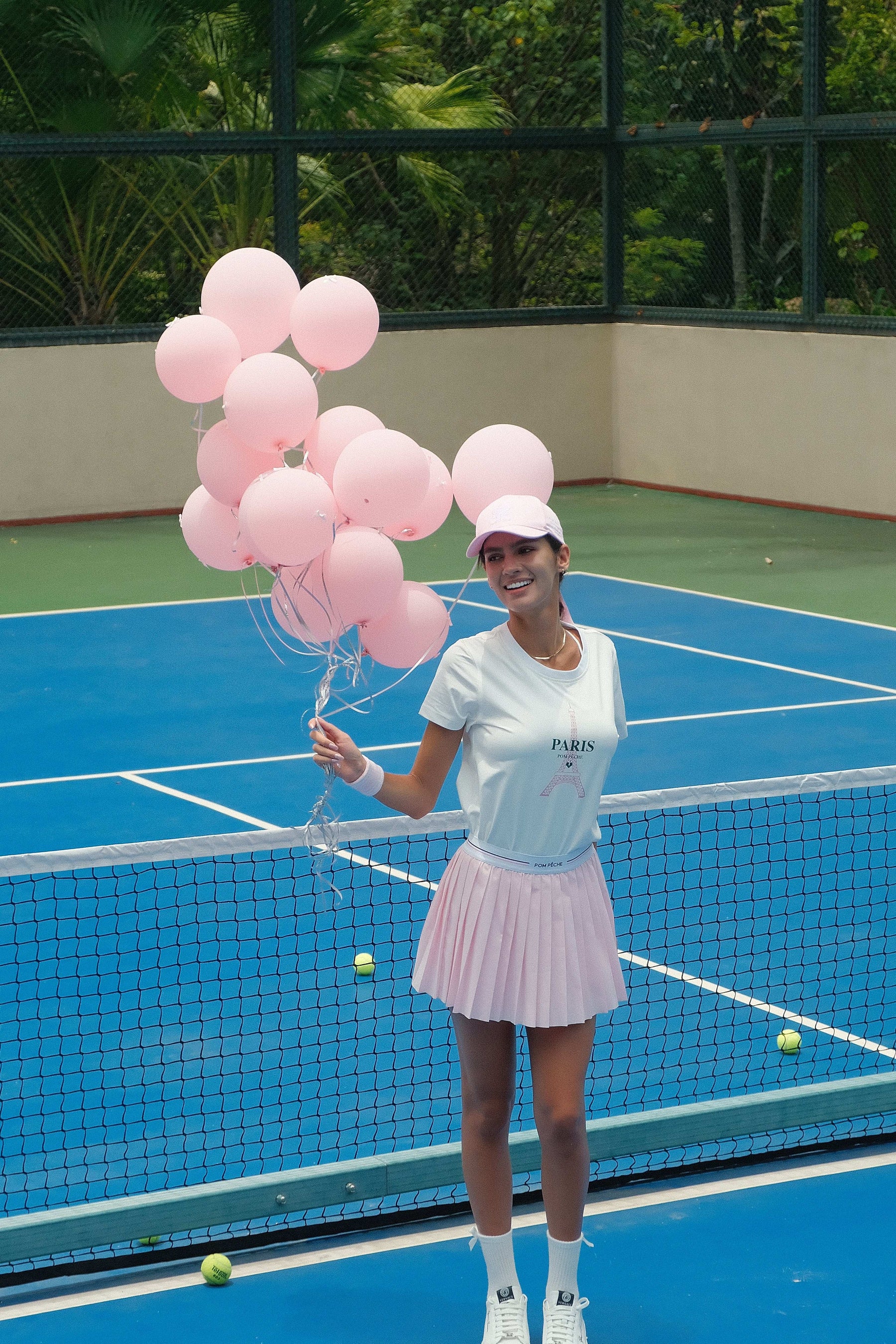 White sports tee with a soft pink 'Paris' graphic and brand logo, designed for comfort and style during activities.