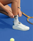 White ankle tennis socks with black bow detail and Pom Pêche logo, styled on the court.