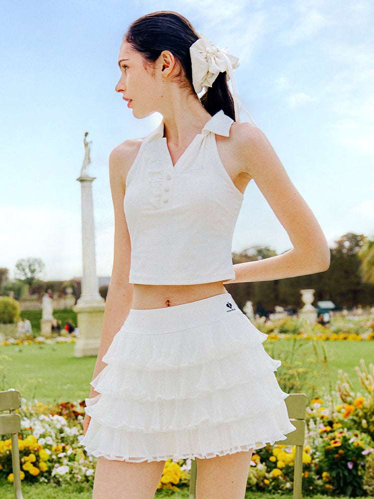 White cropped tennis top with ruffled collar and sleeveless design, featuring a subtle logo for a chic, sporty look.