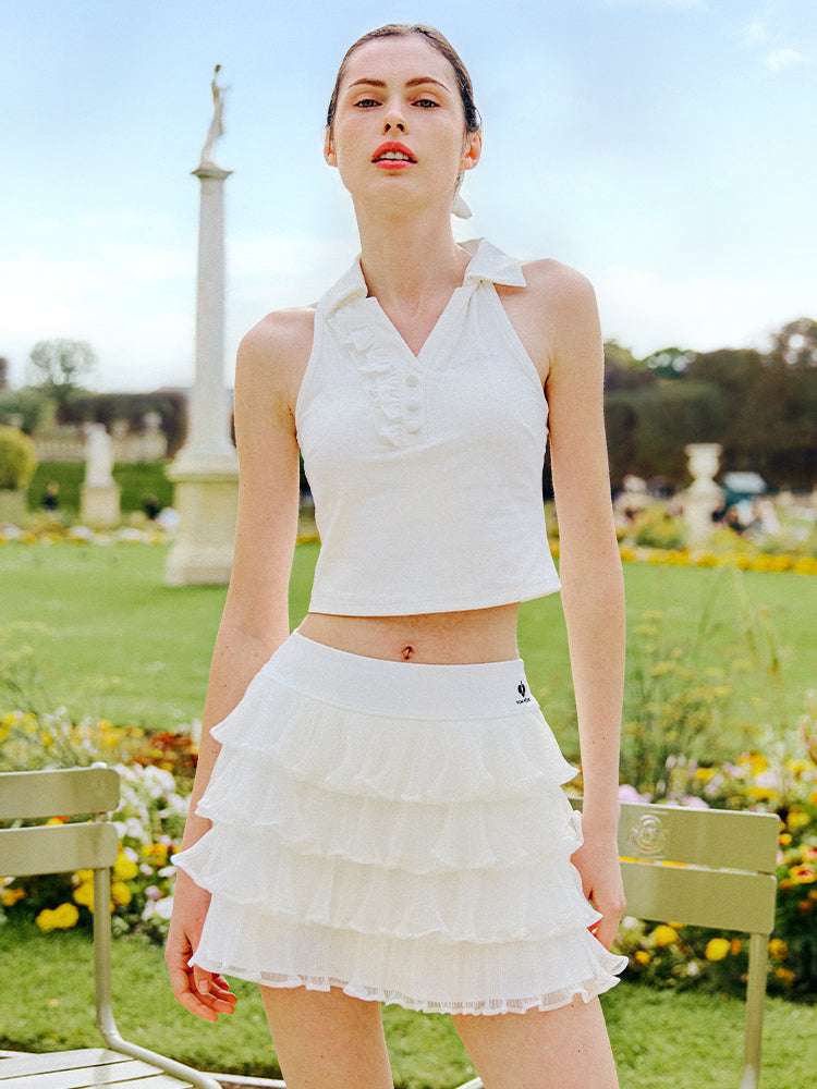White cropped tennis top with ruffled collar and sleeveless design, featuring a subtle logo for a chic, sporty look.
