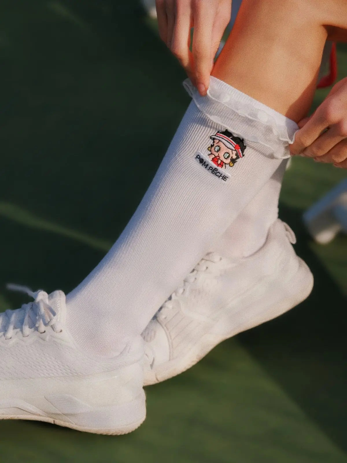 Person wearing white socks with a cartoon character design on a blurred outdoor background