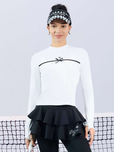 White long-sleeve top with a smooth silhouette and contrast bow detail, styled on the tennis court.