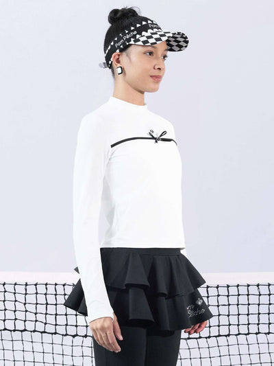 White long-sleeve top with a smooth silhouette and contrast bow detail, styled on the tennis court.