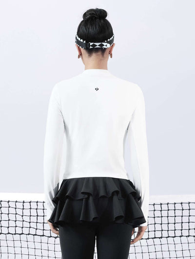 White long-sleeve top with a smooth silhouette and contrast bow detail, styled on the tennis court.