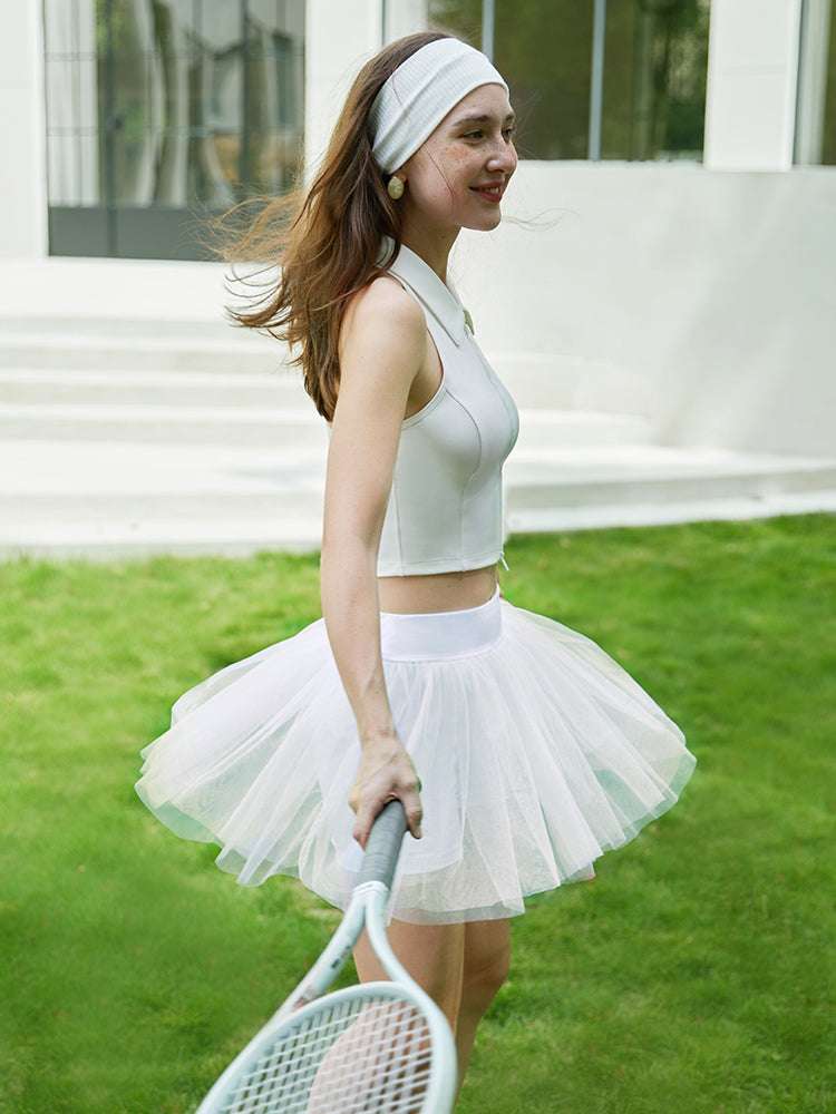 Model wearing a white tulle puff tennis skirt outdoors, showing airy layered mesh and a high-waisted athletic tennis skirt silhouette.