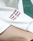 White zip-up hoodie with bow detail on the hood and embroidered logo, perfect for warm-ups or everyday wear.