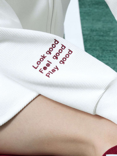 White zip-up hoodie with bow detail on the hood and embroidered logo, perfect for warm-ups or everyday wear.