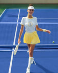 Yellow and white cropped graphic tennis tee with a printed design, offering a lightweight, breathable feel for warm-weather play.